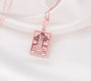 The Tower tarot card rose gold boho chic pendant necklace , depicted in a striking rose gold color features a tall, imposing structure being struck by highlighting the crumbling tower as it tilts precariously. Two figures are shown falling from the structure, symbolizing sudden upheaval or chaos. The background is often minimal, allowing the vivid rose gold tones to emphasize the tower's destruction and the sense of unexpected change or revelation it represents.