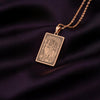 A rectangular pendant with an engraved design is displayed against a dark purple background.