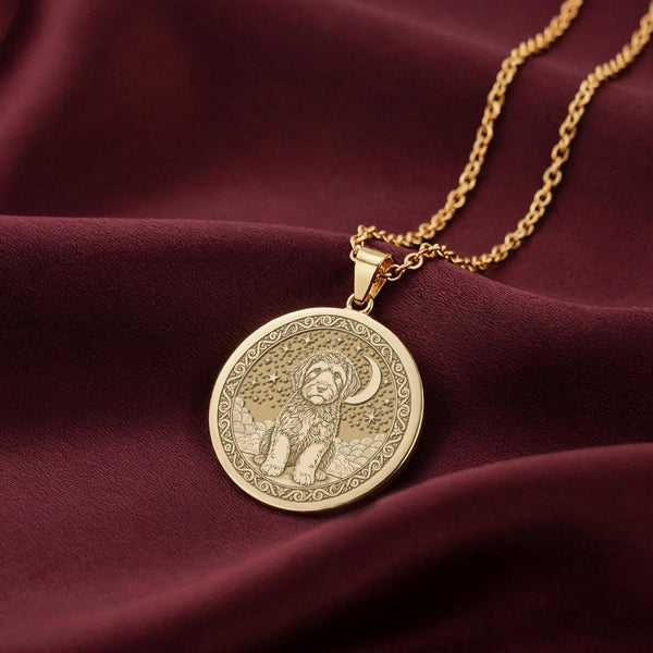 A handmade 14K gold plated round necklace with a highly detailed celestial pet portrait of a Portuguese Water Dog. The dog is engraved sitting on clouds under a starry night sky.