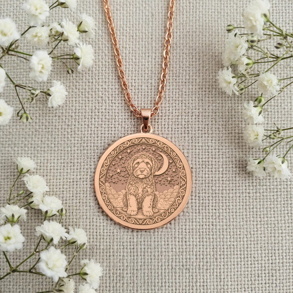 An elegant rose gold plated coin pendant celebrating a beloved canine companion. The engraved art shows a Portuguese Water Dog on a cloud, a beautiful piece of memorial jewelry.
