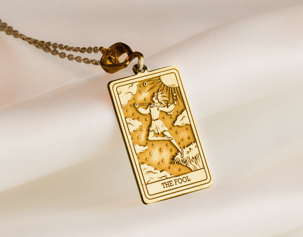 gold The Fool tarot card charm necklace, a vintage pendant necklace ideal for layering. This unique pendant makes a perfect good luck charm, protection necklace, or birthday pendant, adding mystique to a personalized charm necklace collection