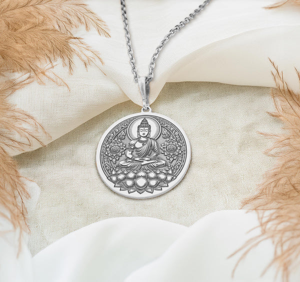 Buddha figure seated in meditative lotus pose (Padmasana) upon a blooming lotus flower base. The bright, cool shine of the polished 925 sterling silver beautifully accentuates the detailed lines of the central deity and the surrounding ornate floral mandala-style patterns filling the circular frame.