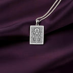 A striking 925 sterling silver tarot card pendant of the goddess Bastet. This piece of witchy jewelry is styled on a dark purple silk background.