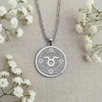 Personalized Sterling Silver Taurus Necklace with its classic glyph and flower details. This spiritual and engravable pendant is a perfect custom gift for astrology enthusiasts and Taurus.