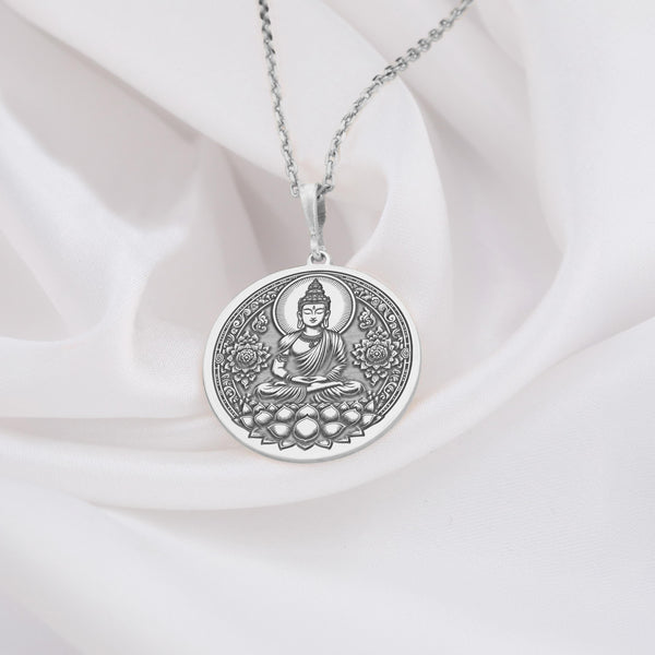 Buddha figure seated in meditative lotus pose (Padmasana) upon a blooming lotus flower base. The bright, cool shine of the polished 925 sterling silver beautifully accentuates the detailed lines of the central deity and the surrounding ornate floral mandala-style patterns filling the circular frame.