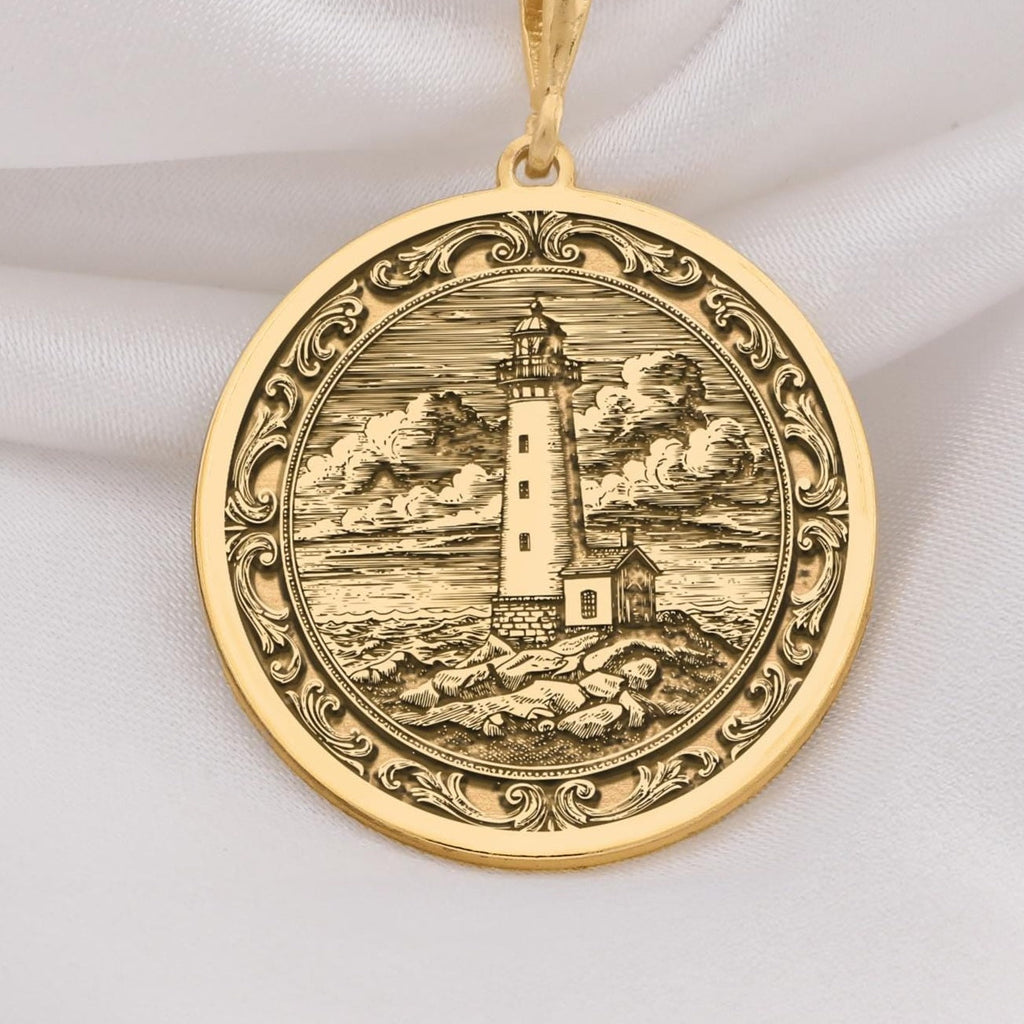 14K Solid Gold Lighthouse Medallion featuring coastal beacon with cloudy sky and rocky shore. Detailed maritime talisman with ornate border and textured seascape.
