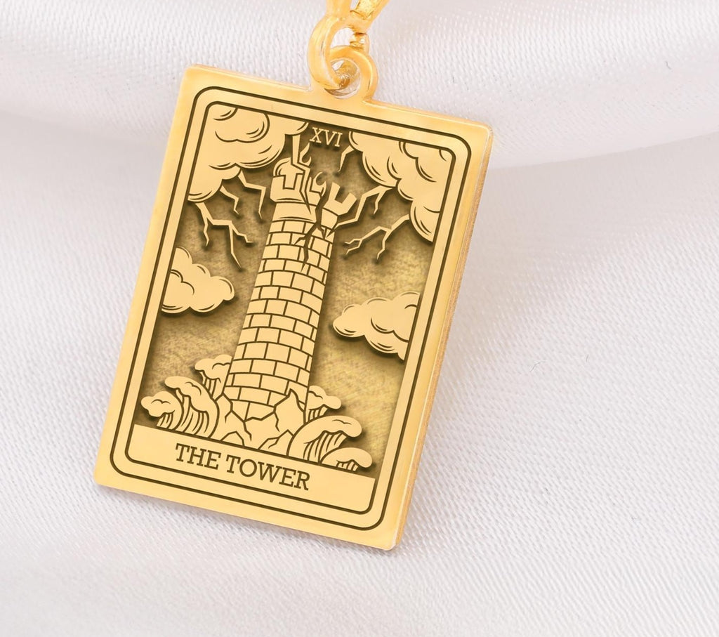 The Tower tarot card  boho chic pendant necklace , depicted in a striking gold color features a tall, imposing structure being struck by highlighting the crumbling tower as it tilts precariously. Two figures are shown falling from the structure, symbolizing sudden upheaval or chaos. The background is often minimal, allowing the vivid gold tones to emphasize the tower's destruction and the sense of unexpected change or revelation it represents.