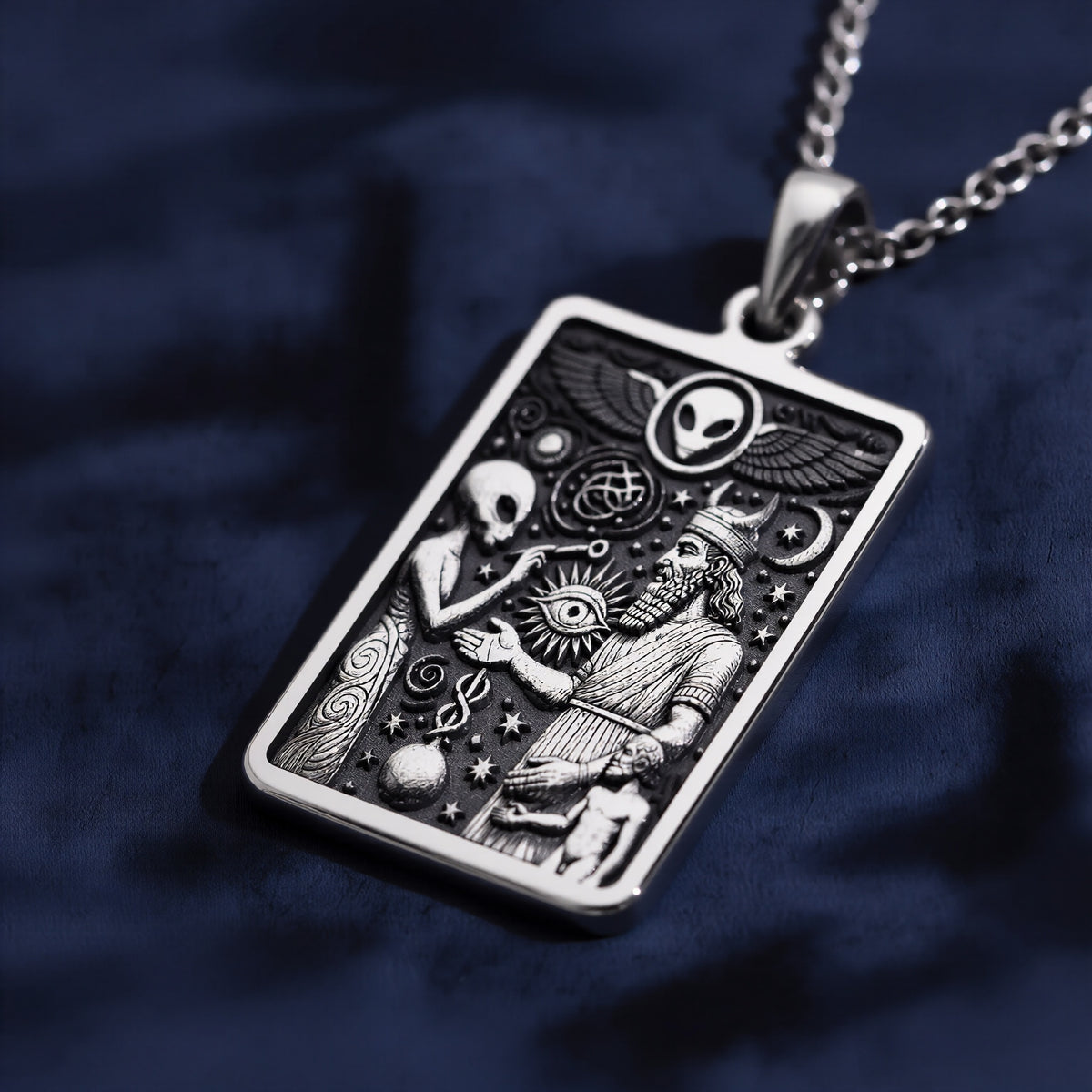 Silver rectangular pendant showcasing intricate line art of mythological figures and an alien head motif. The pendant is attached to a silver chain and rests on a black background.