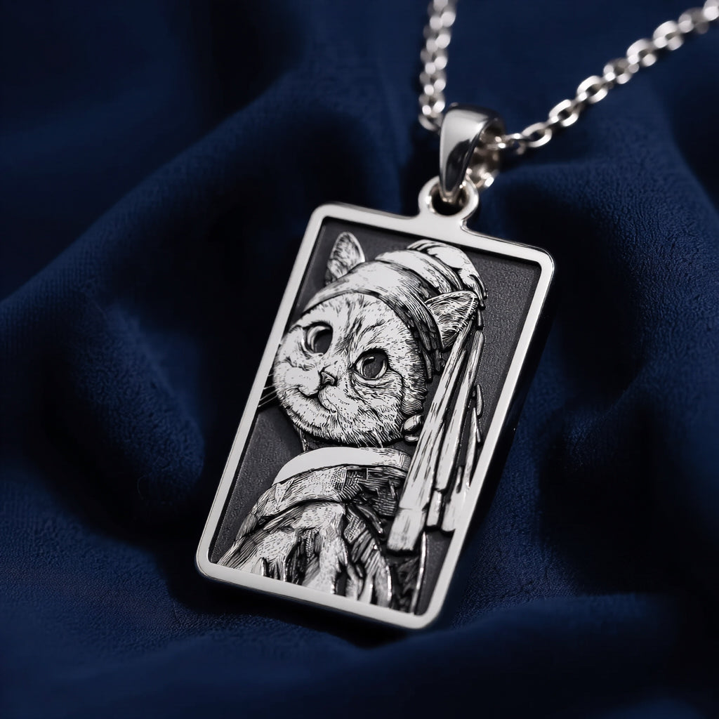 Silver rectangular pendant featuring a detailed line art design of a cat. The piece has a matte surface finish and is displayed on a silver chain.