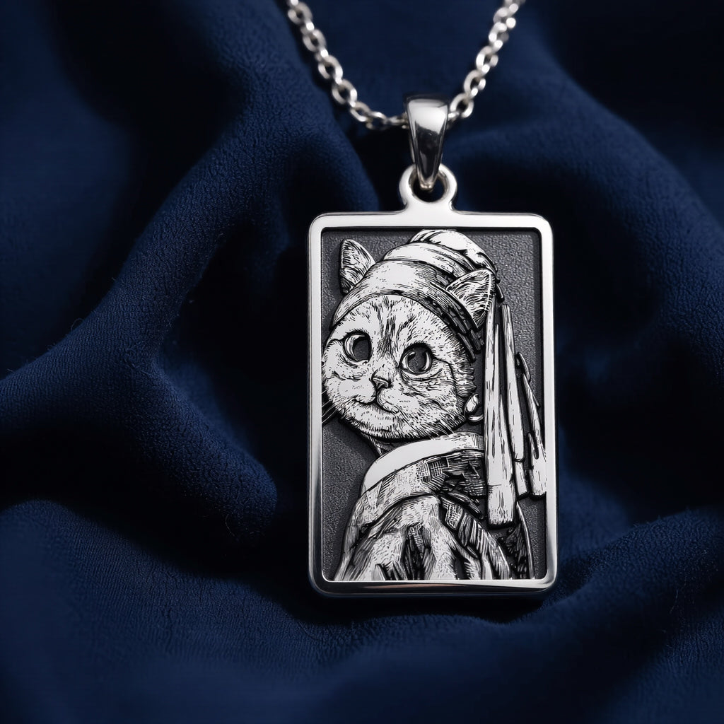 Silver pendant necklace featuring a stylized cat face design with a pearl earring motif. The pendant has a detailed, engraved appearance and is displayed on a black background with scattered gemstone-like objects.