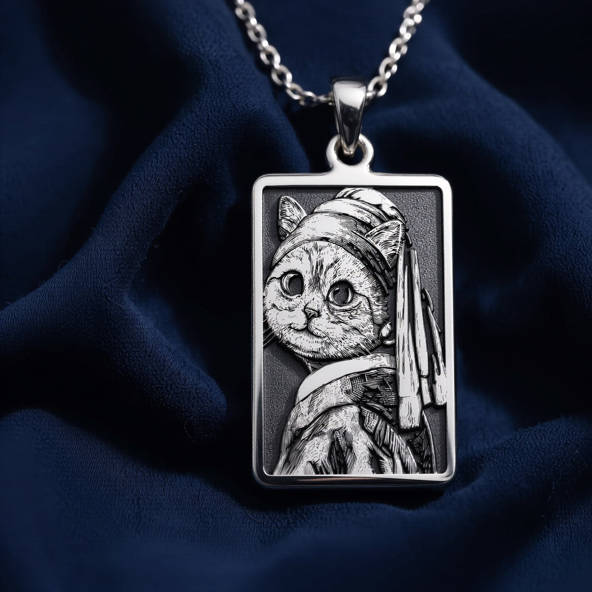 Silver pendant necklace featuring a stylized cat face design with a pearl earring motif. The pendant has a detailed, engraved appearance and is displayed on a black background with scattered gemstone-like objects.