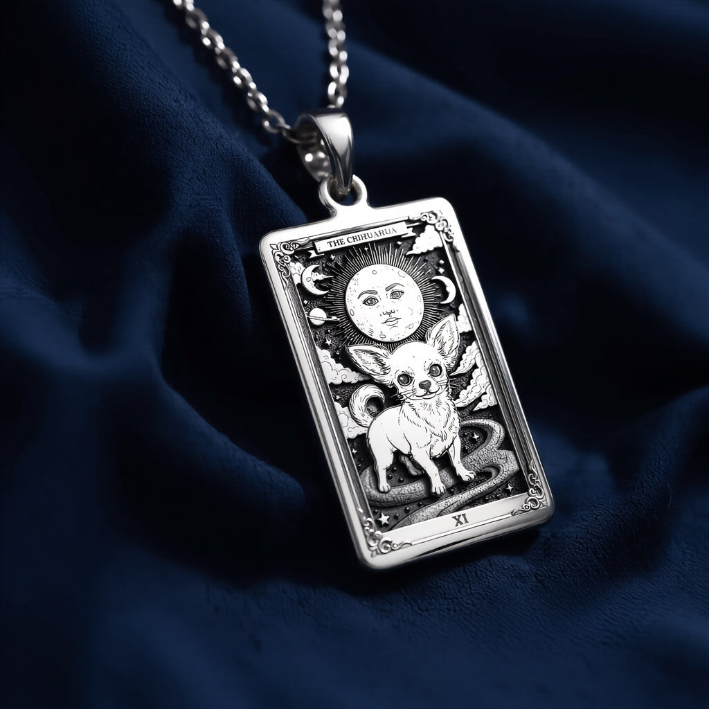 Rectangular sterling silver pendant featuring an engraved Chihuahua tarot card design with celestial moon, stars, and Roman numeral XI; displayed on a fine link chain against dark blue fabric.