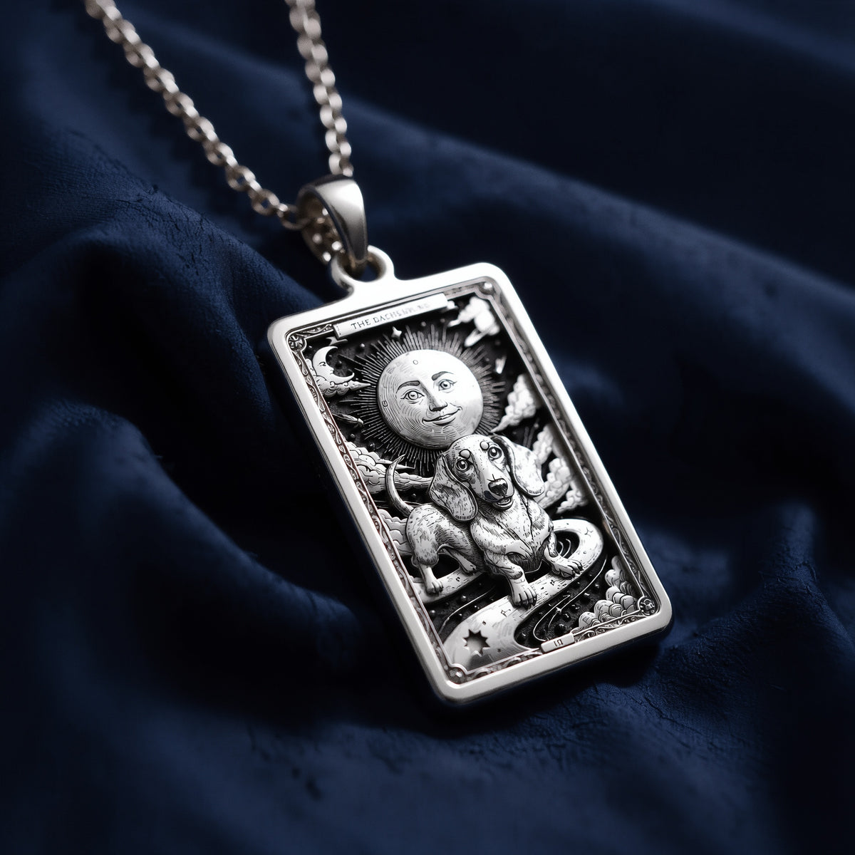 Rectangular sterling silver pendant necklace featuring an intricately engraved dachshund beneath a smiling moon, styled as a tarot-inspired medallion with celestial motifs.