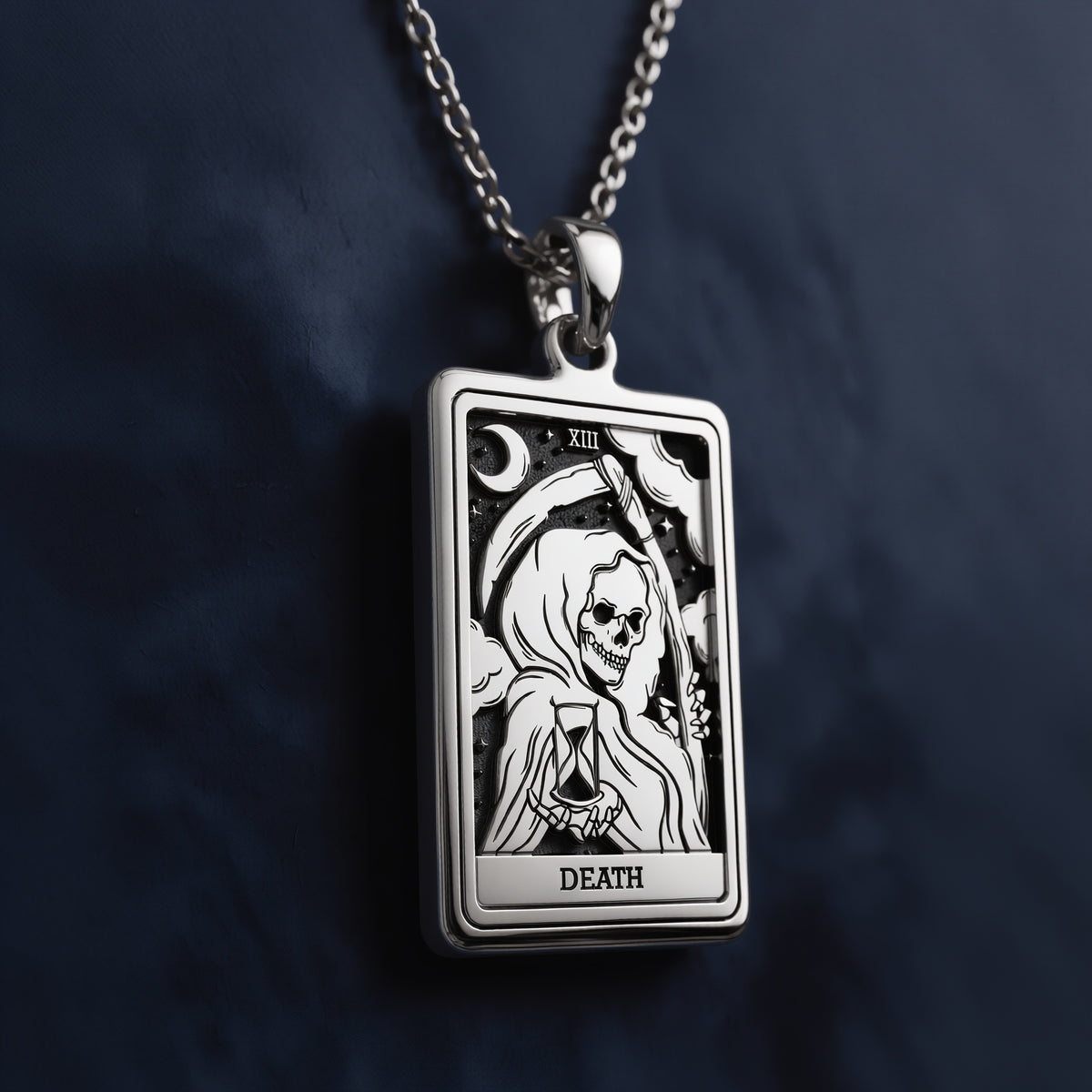 Rectangular silver pendant necklace featuring an engraved Death tarot card design with a skeletal figure, hourglass, crescent moon, stars, Roman numeral XIII, and “DEATH” inscription at the bottom.