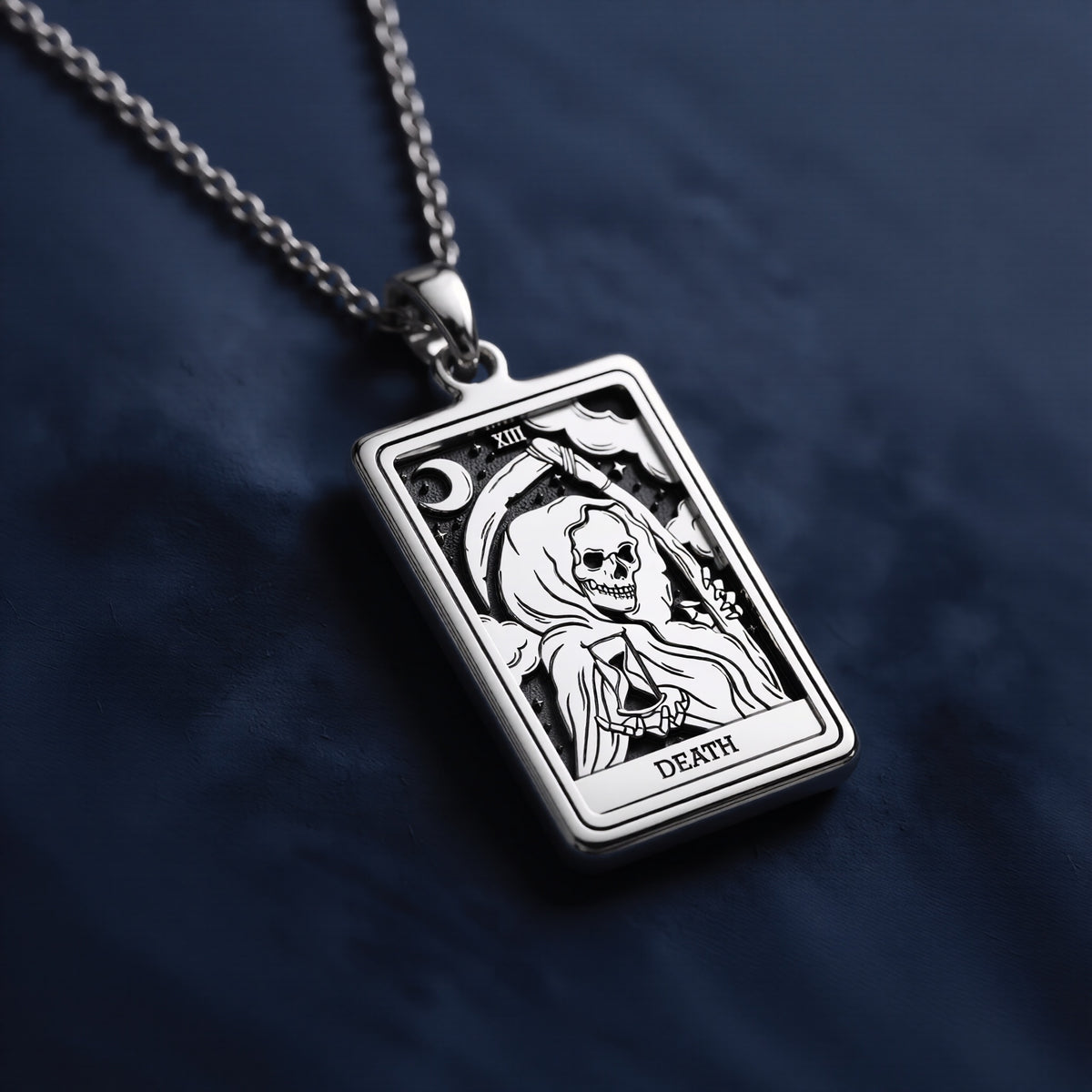 Rectangular sterling silver pendant necklace featuring an engraved Death Tarot card design with a hooded skeletal figure, crescent moon, stars, Roman numeral XIII, and “DEATH” inscription at bottom.