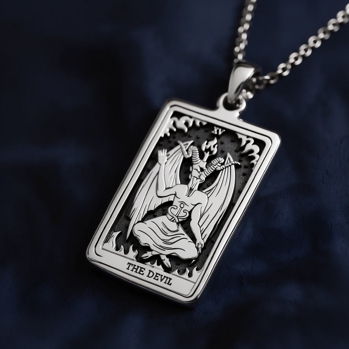 Rectangular silver pendant necklace featuring an engraved Rider Waite Tarot "The Devil" card (XV) with a kneeling horned figure, flames, and Roman numeral XV; suspended on a fine link chain.