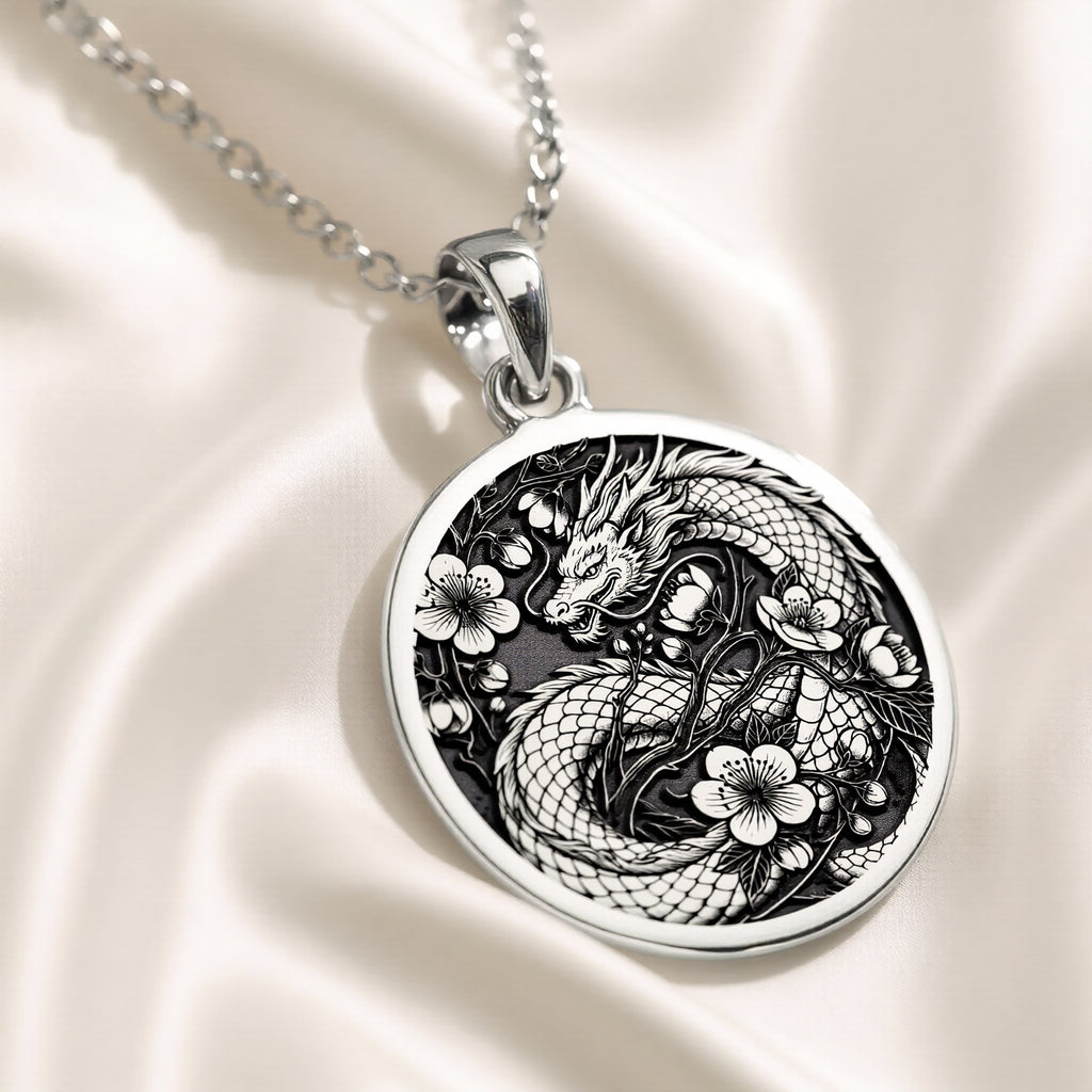 Silver pendant featuring an intricate Japanese dragon motif with detailed scales and flowing lines. The pendant has a polished surface finish and is suspended from a delicate silver chain