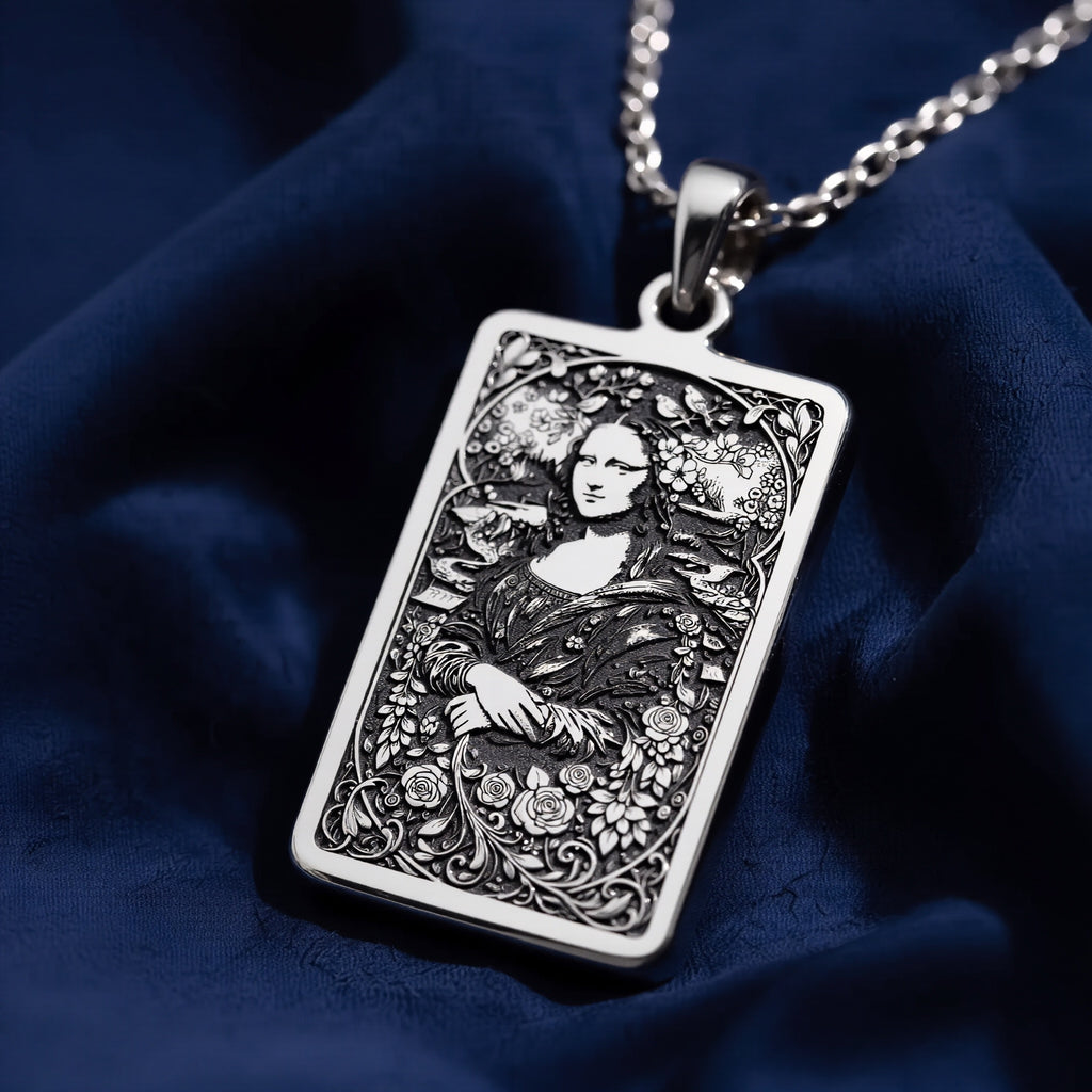 Silver plated rectangular pendant necklace with an intricate engraved design of a woman amidst elaborate floral and vine patterns. The piece is set against a black backdrop with scattered gemstone elements.
