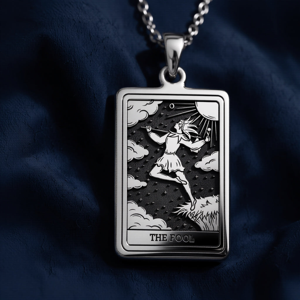 Rectangular sterling silver pendant featuring an engraved depiction of The Fool tarot card, showing a figure walking over clouds with staff and sun above, set in polished 925 silver frame with "THE FOOL" inscription at bottom.