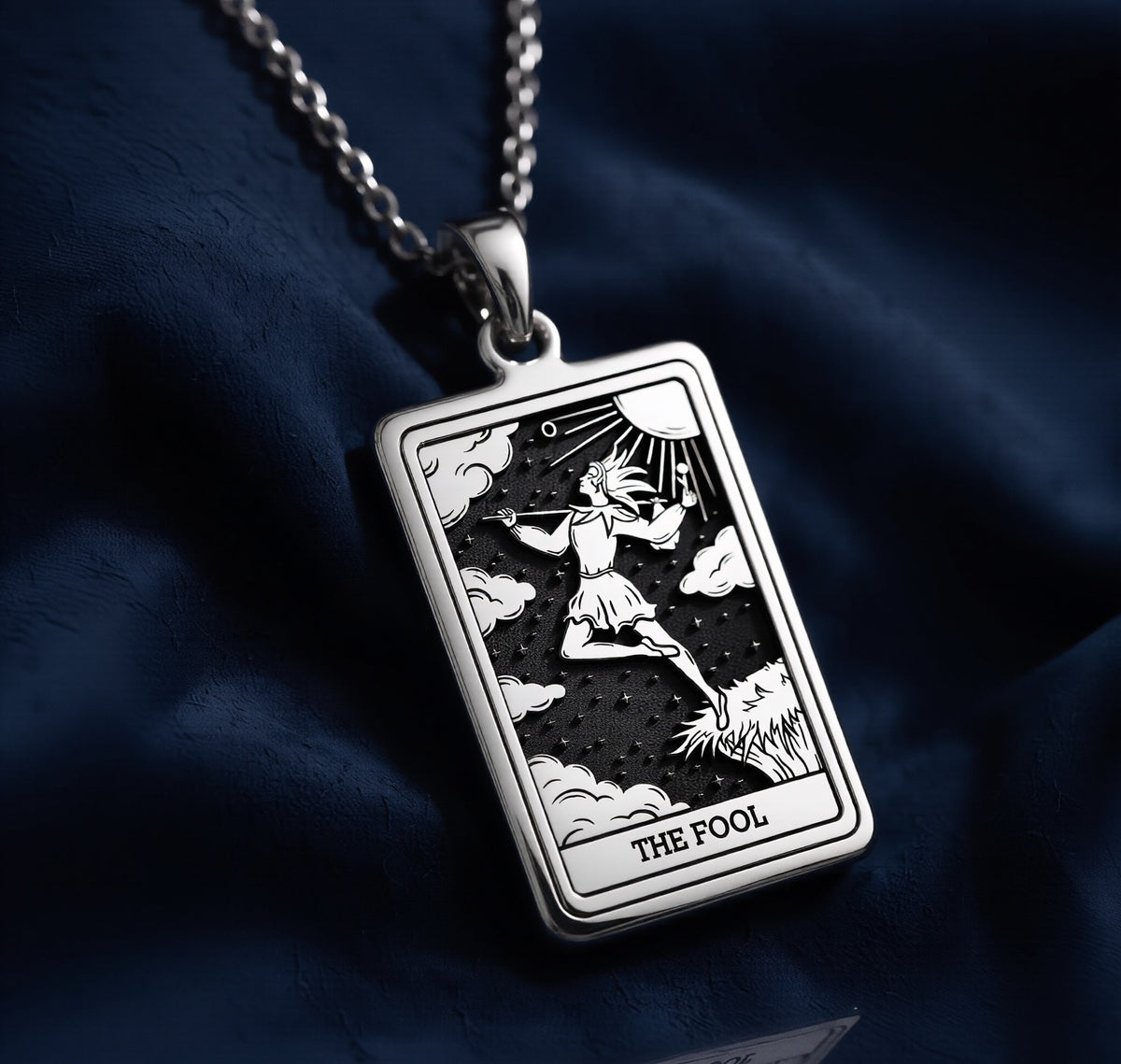 Rectangular 925 sterling silver pendant necklace featuring an engraved depiction of The Fool tarot card Major Arcana, with a figure leaping toward the sun above clouds, set against a dark oxidized background.