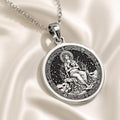 Silver plated circular medallion pendant featuring an engraved depiction of a seated female figure surrounded by foliage. The pendant is attached to a silver chain and shown in a front view.