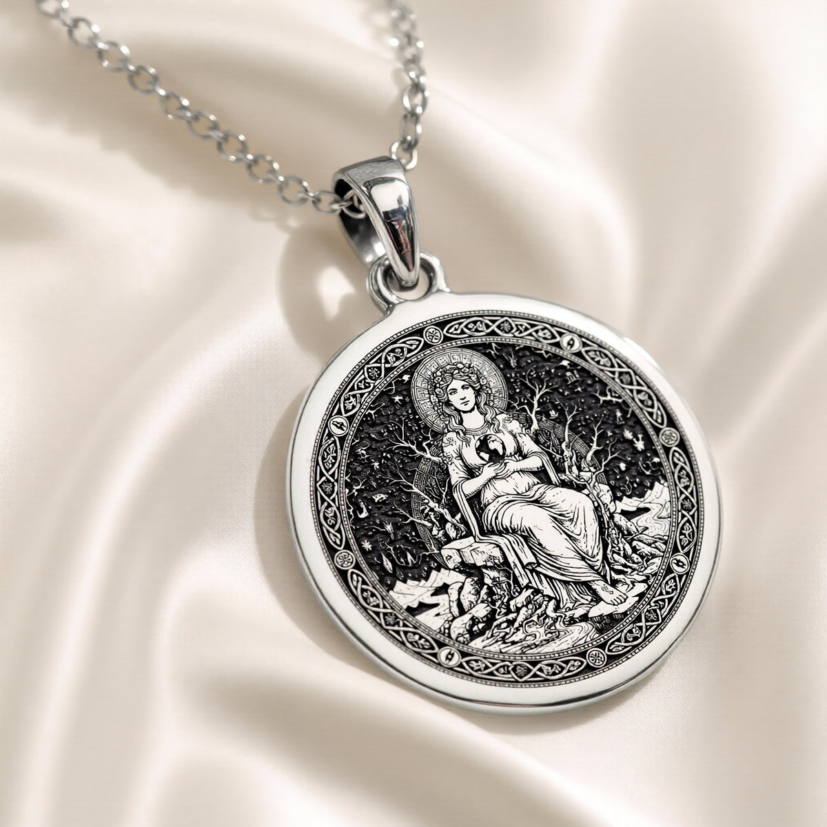 Silver plated circular medallion pendant featuring an engraved depiction of a seated female figure surrounded by foliage. The pendant is attached to a silver chain and shown in a front view.