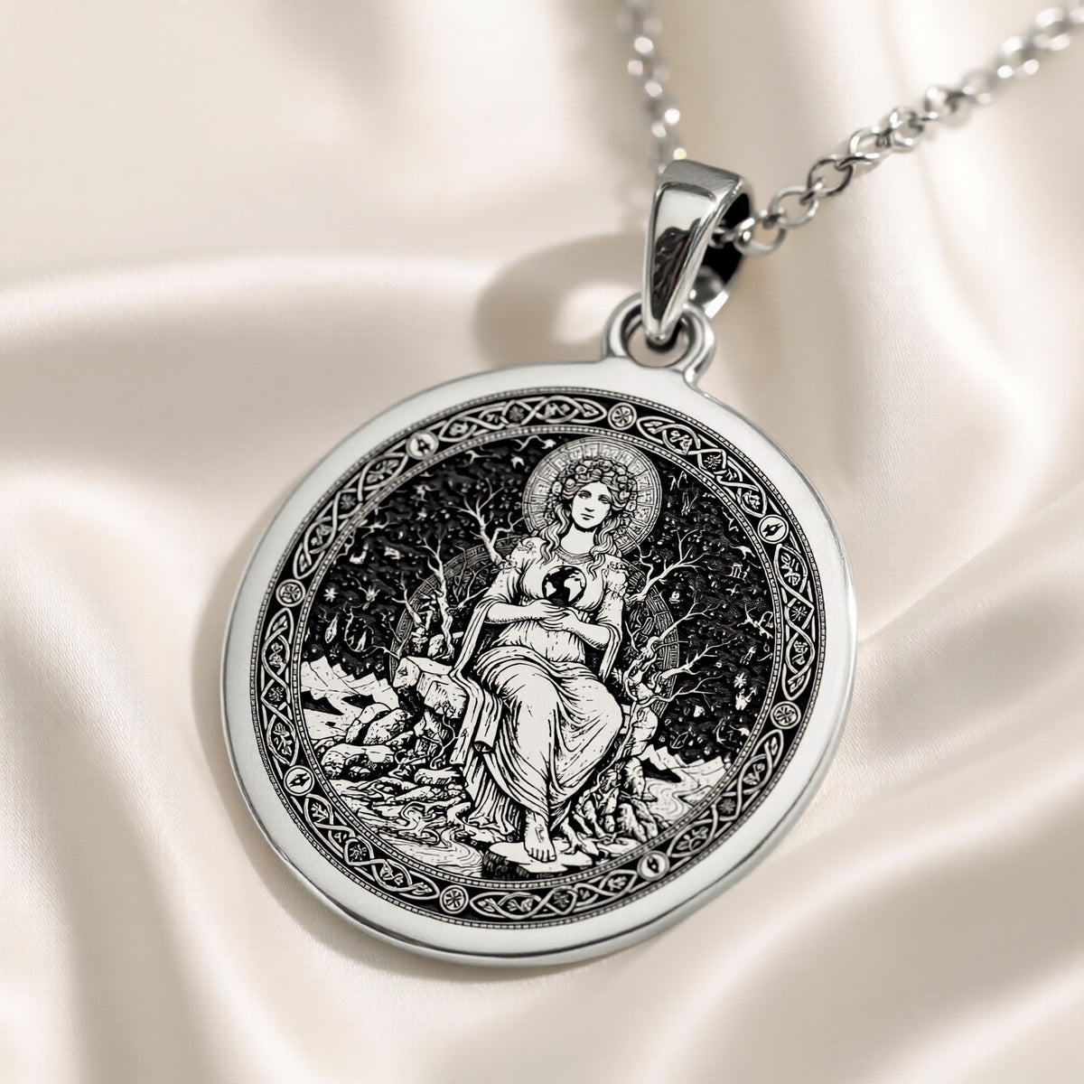 Silver plated circular medallion pendant featuring an engraved depiction of a seated female figure surrounded by foliage. The pendant is attached to a silver chain and shown in a front view.