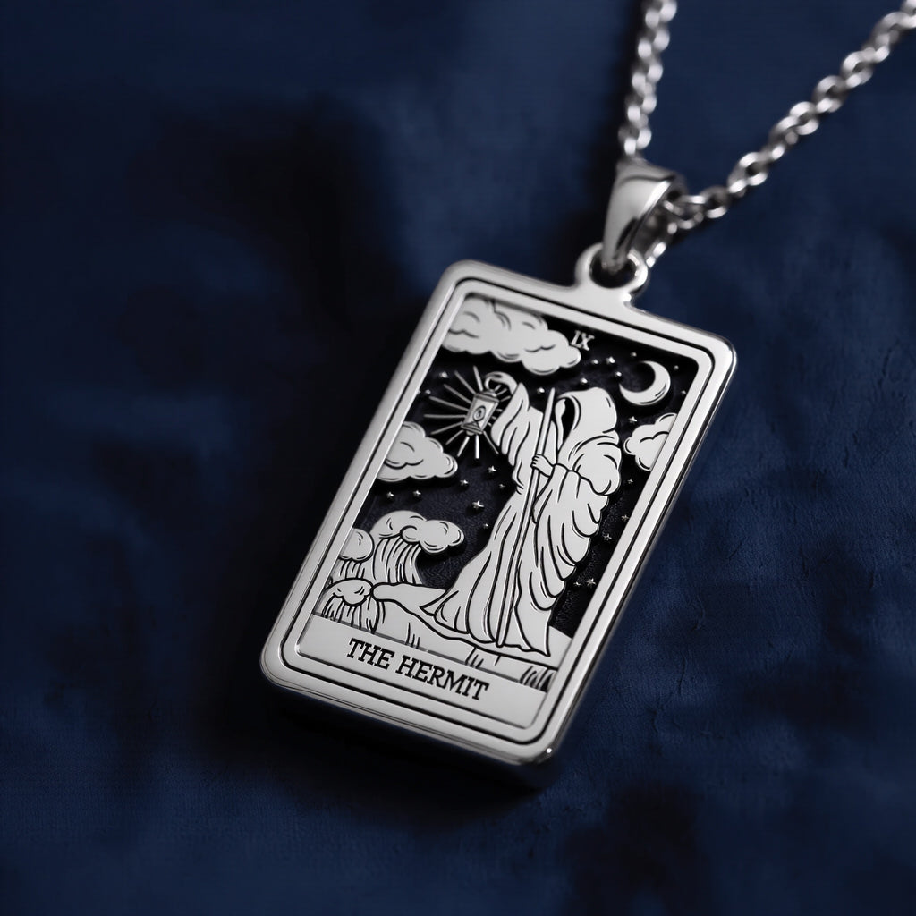 Rectangular sterling silver pendant necklace featuring an engraved depiction of The Hermit tarot card, showing a hooded figure holding a lantern beneath a crescent moon and stars.