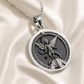 Silver circular pendant featuring an intricate Aztec winged deity design resting on a serpentine structure. The pendant is attached to a silver chain