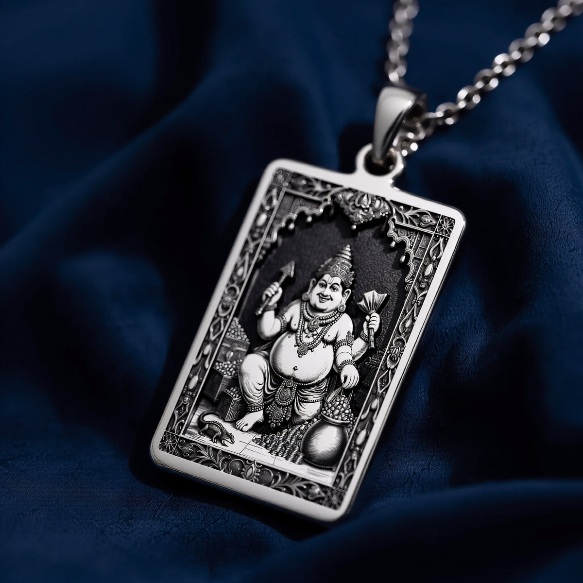 Silver rectangular pendant featuring a detailed relief carving of the Kubera God of Wealth motif enclosed in a frame. The pendant is displayed on a silver chain, highlighting the cool tone of the metal.
