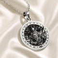 Silver pendant featuring an intricate Odin Allfather Viking motif with a detailed surface finish. The pendant is displayed on a delicate chain, viewed from a slight angle against a dark green velvet background