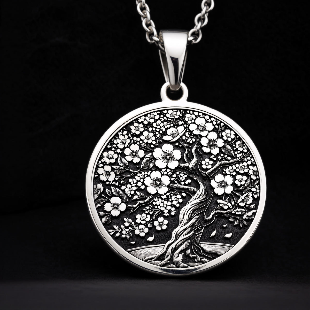 Sakura Tree Pendant in sterling silver showing the front engraving of a blooming cherry blossom tree with falling petals.