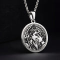 Silver toned circular pendant showing a detailed relief carving of Shiva and Parvati. This necklace features a silver chain and is displayed against a dark blue fabric background.