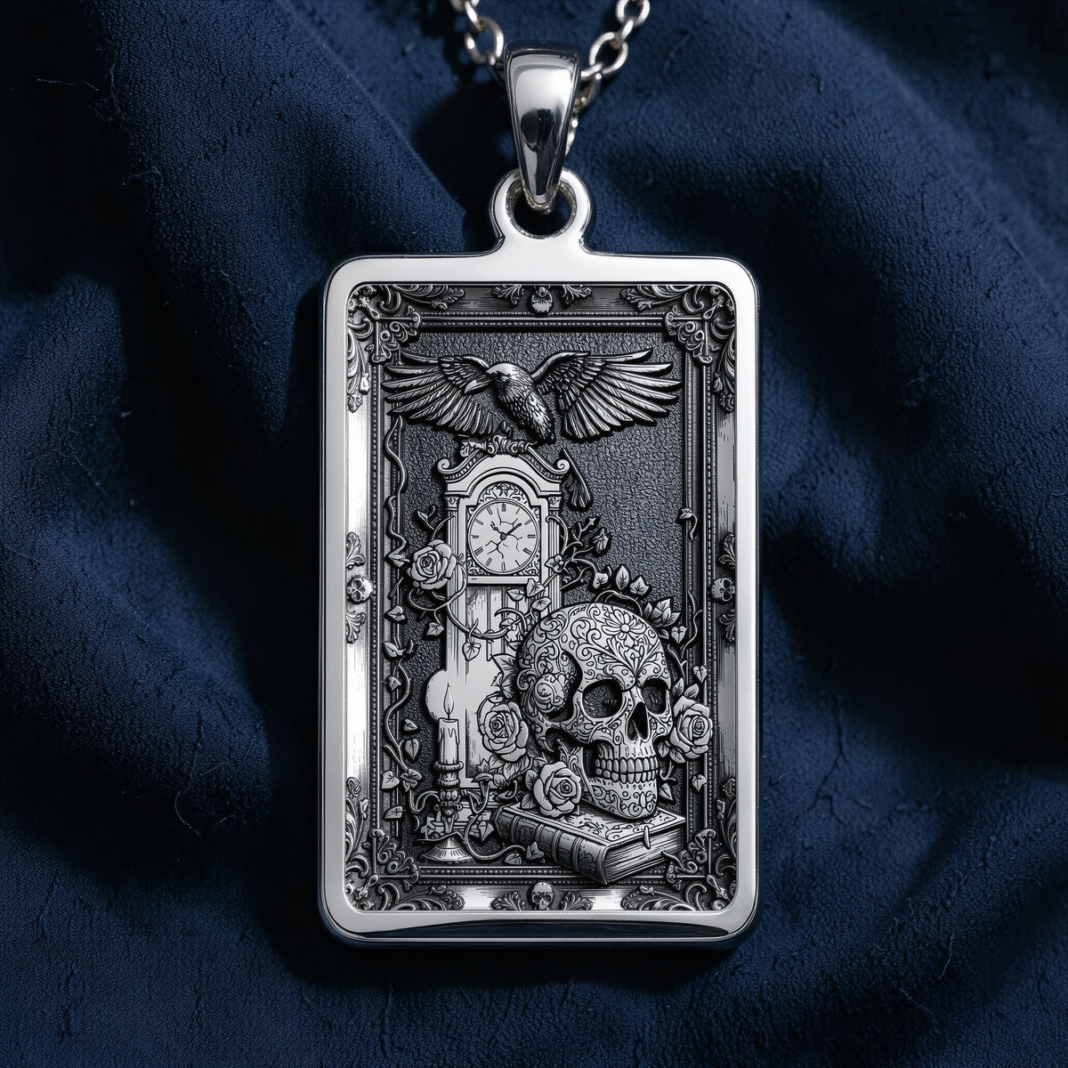 Silver rectangular pendant featuring an intricate engraved design of a skull, clock, and eagle. This piece is displayed on a silver chain surrounded by loose gemstones and dark textile.