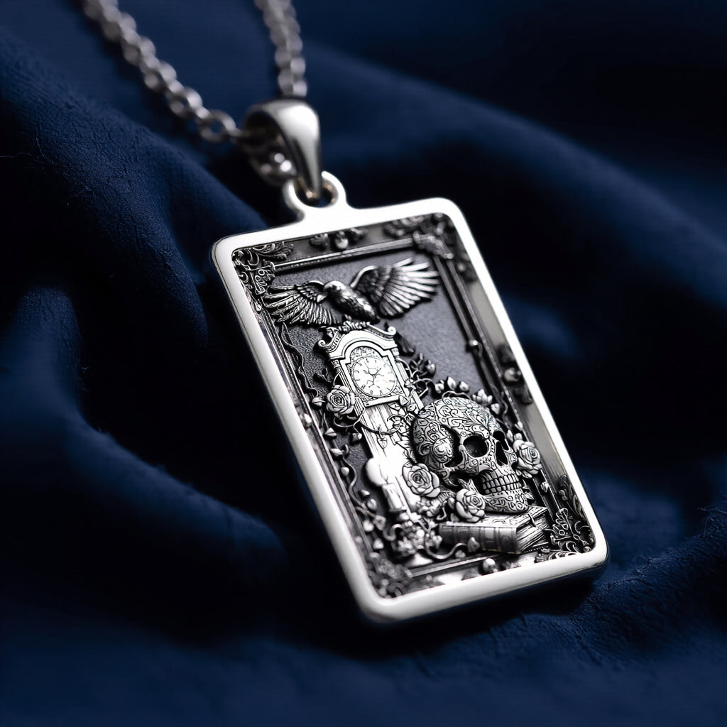 Silver pendant featuring a detailed skull tarot design with gothic style details. The pendant has a textured, antique finish and is displayed on a black background with scattered gemstone-like shapes.