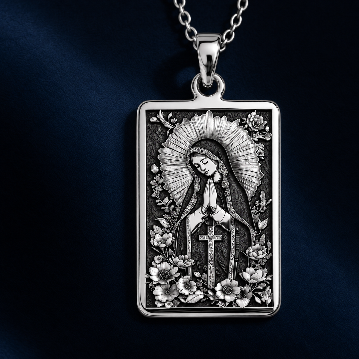 Silver pendant necklace featuring a detailed Virgin Mary Blessed Mother design with intricate scrollwork and a crown motif. The piece has a polished finish and is displayed on a dark background with various gemstones.