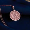 Rose gold plated Durga pendant necklace displaying the Hindu goddess of power and protection riding her tiger. This circular medallion features beautifully detailed engravings showing multi-armed Durga holding traditional weapons and symbolic items. The warm rose gold plating creates an elegant contrast with the antique finish of the engraved details, all suspended from a matching chain against soft white fabric. This spiritual jewelry piece celebrates divine feminine energy,