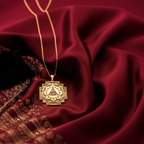 This 14k gold plated Ganesh Yantra Necklace, a powerful spiritual amulet for success, is shown in a luxurious close-up from a different angle. Presented on rich burgundy silk, the intricate handcrafted engraving is emphasized, highlighting its quality as a premium meditation gift. This personalized sacred geometry talisman is for removing obstacles and is available in 925 sterling silver.