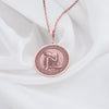 Rose gold plated Buddha pendant necklace showcasing a peaceful meditation scene. This circular medallion features beautifully detailed engravings of Buddha in restful contemplation, head gently resting on hand. The warm rose gold plating creates an elegant contrast with the antique finish of the intricate border details, all suspended from a matching chain against soft white fabric.