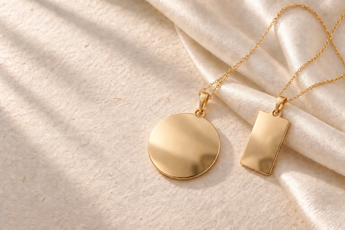 Mirror-polished round and rectangular gold pendants on soft ivory satin