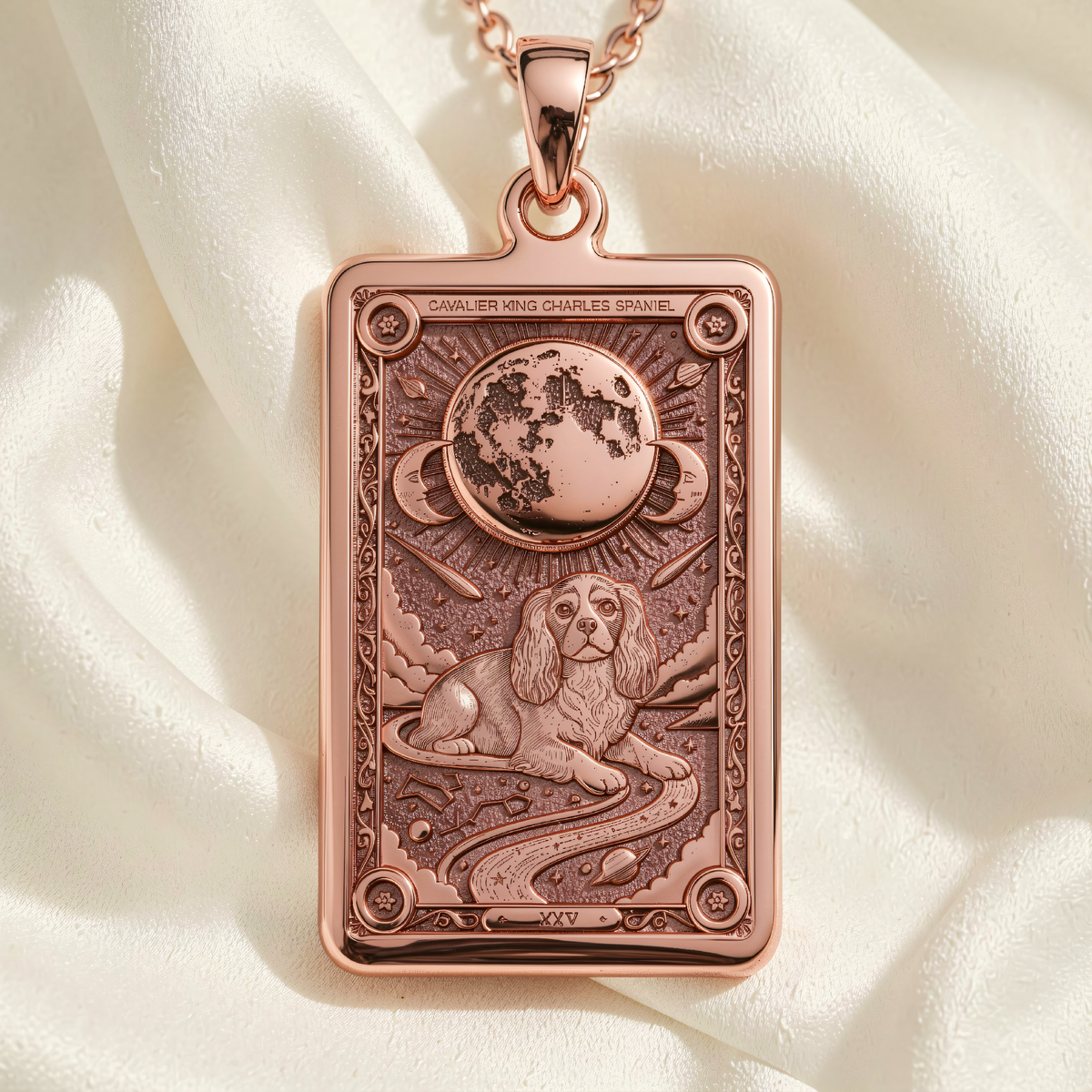 Rose gold plated rectangular pendant with engraved Cavalier King Charles Spaniel, moon and stars on white fabric.