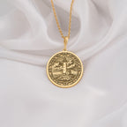 14K Solid Gold Lighthouse Medallion featuring coastal beacon with cloudy sky and rocky shore. Detailed maritime talisman with ornate border and textured seascape.