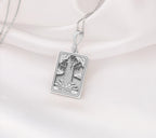 The Tower tarot card silver boho chic pendant necklace , depicted in a striking silver color features a tall, imposing structure being struck by highlighting the crumbling tower as it tilts precariously. Two figures are shown falling from the structure, symbolizing sudden upheaval or chaos. The background is often minimal, allowing the vivid silver tones to emphasize the tower's destruction and the sense of unexpected change or revelation it represents.