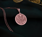 Firebird Mythical Phoenix Pendant Necklaces Rose 14K Rose 14K 14K Rose 14K 14K Rose Gold Plated circular pendant necklace with ornate bird design on dark fabric.