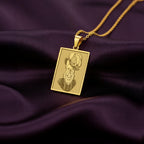 Close-up shot of the 14K Solid Gold French Bulldog pendant. The intricate engraving details of the dog's face, ruffled collar, and feathered hat are clearly visible.