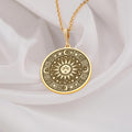 Sun Celestial Necklace: 14K gold round medallion pendant with engraved sun face, stars, and moon symbols on white fabric.