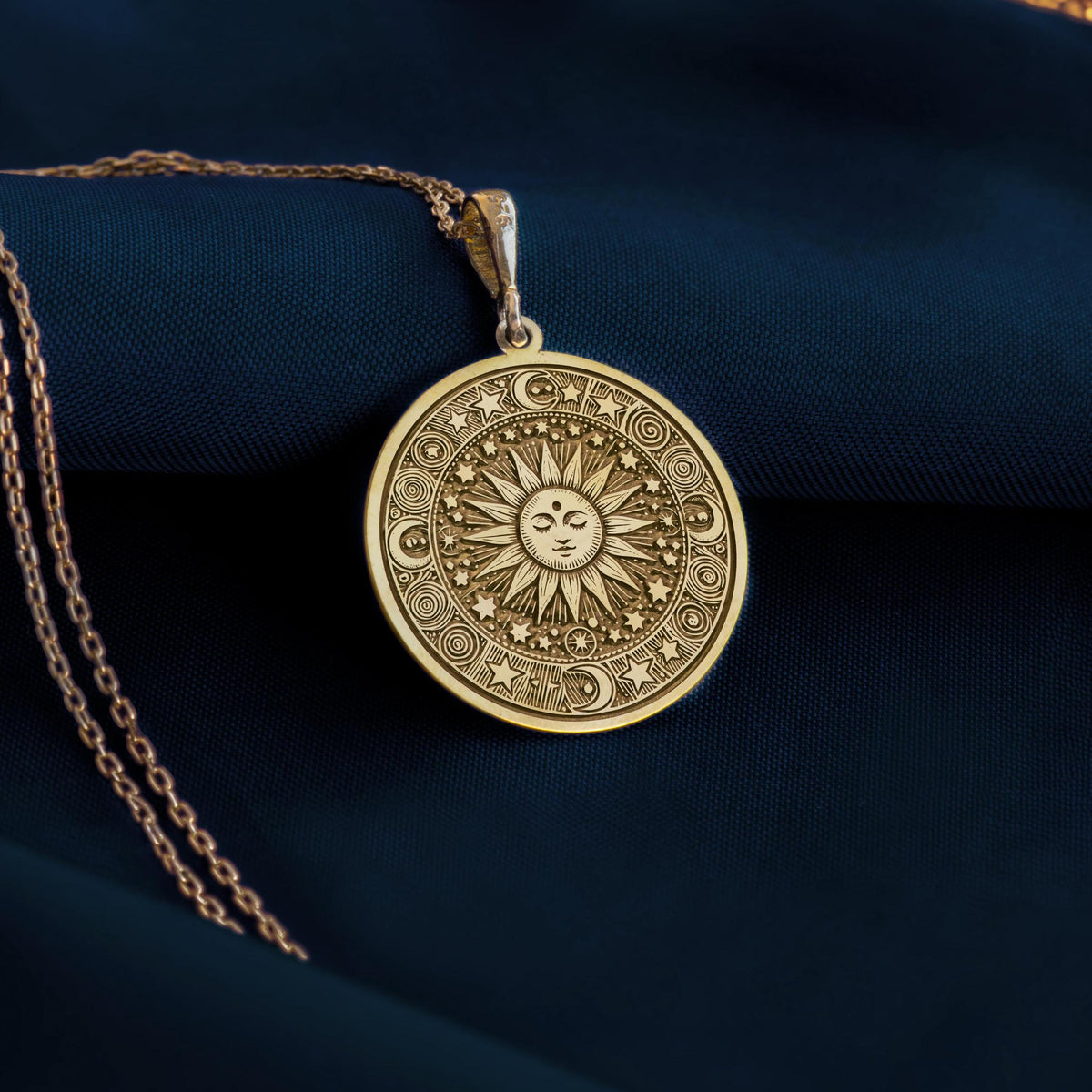 Sun Celestial Necklace: 14K gold pendant showing an engraved sun face with rays, stars, and cosmic symbols.
