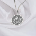 Silver circular pendant featuring an embossed design of the elephant-headed deity Ganesha with intricate detailing. The pendant hangs from a silver chain.