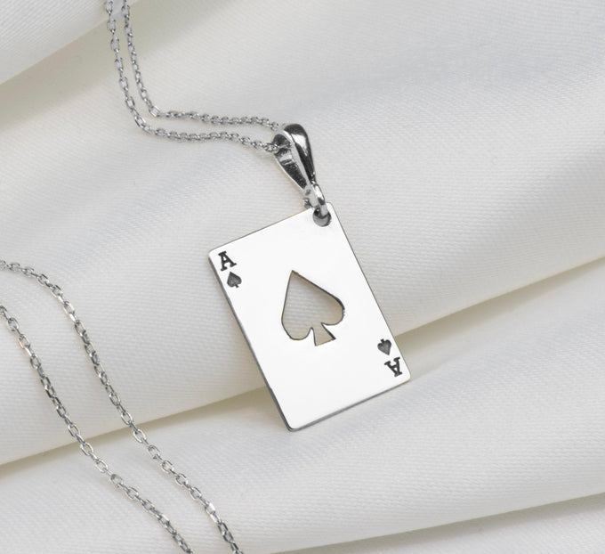 Silver pendant necklace featuring an Ace of Spades design with a four of Hearts and Ace of Diamonds motif. The pendant has a polished surface finish and is attached to a silver chain.