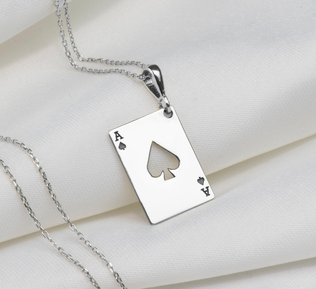 Silver pendant necklace featuring an Ace of Spades design with a four of Hearts and Ace of Diamonds motif. The pendant has a polished surface finish and is attached to a silver chain.